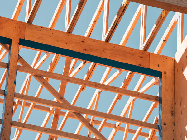 Timber roof and wall framing against a blue sky
